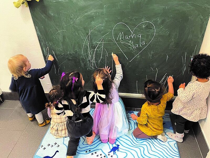 Kinder schreiben und bemalen eine Kreidetafel