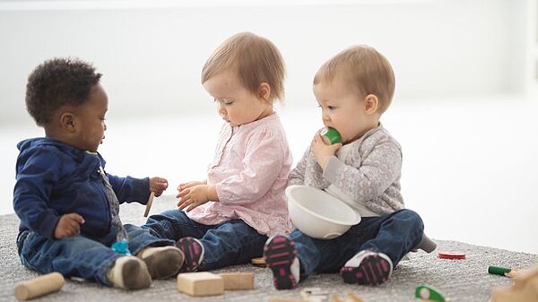 Leben mit Kindern Drei Kinder spielen mit Bauklötzen